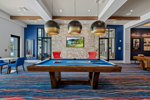 A pool table with a red cloth and a picture of a landscape hanging on the wall.