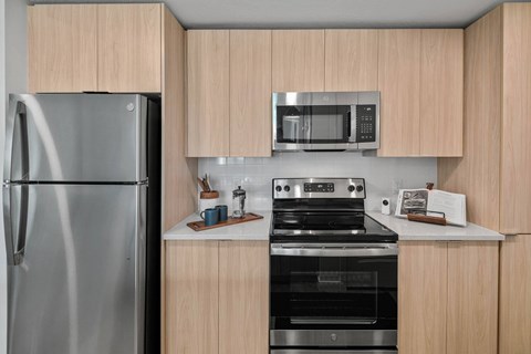 A kitchen with a stainless steel refrigerator, a microwave, and a stove top oven.