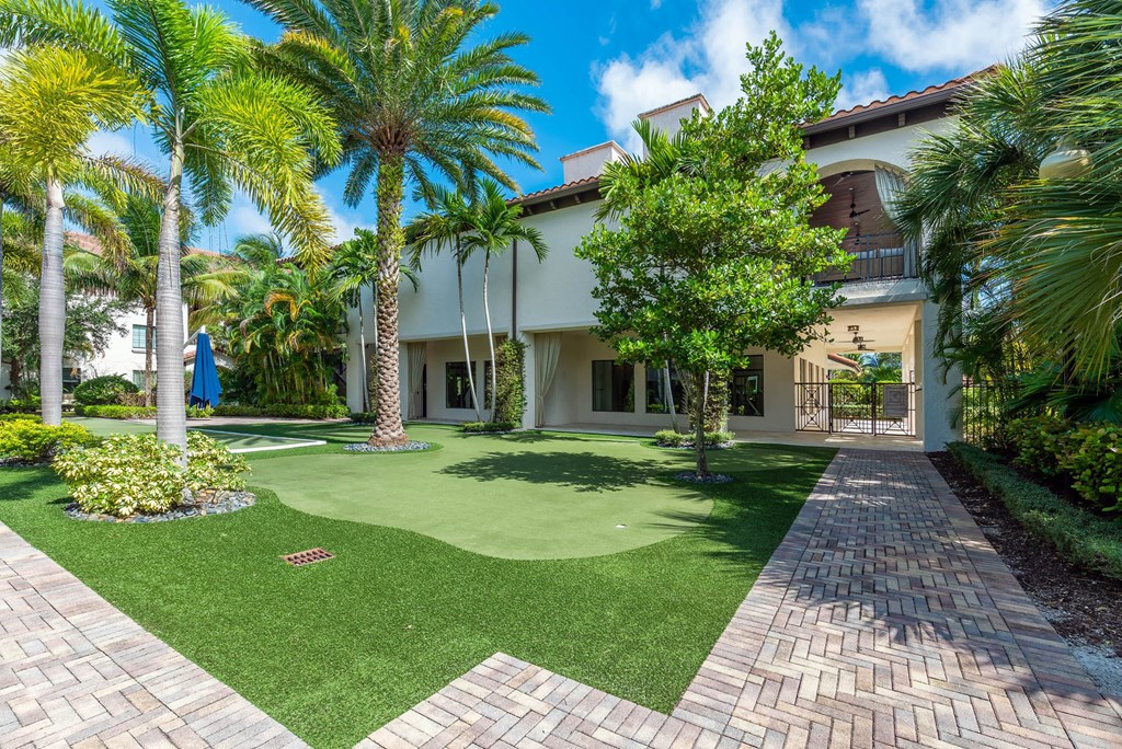 A house with a green lawn and palm trees in front.