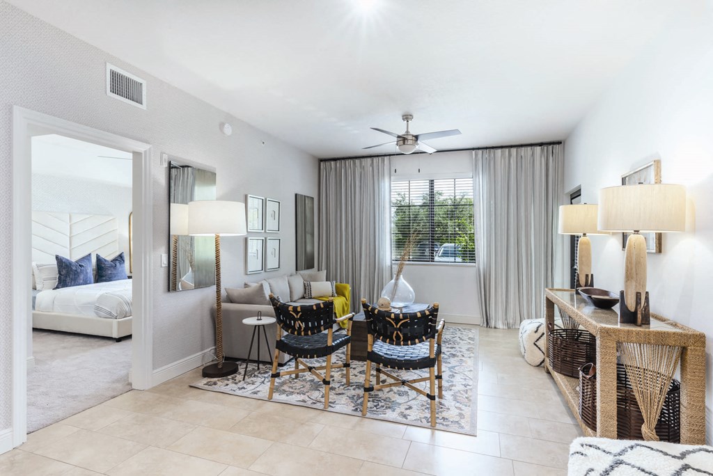 A well-lit living room with a sofa, chairs, and a ceiling fan.