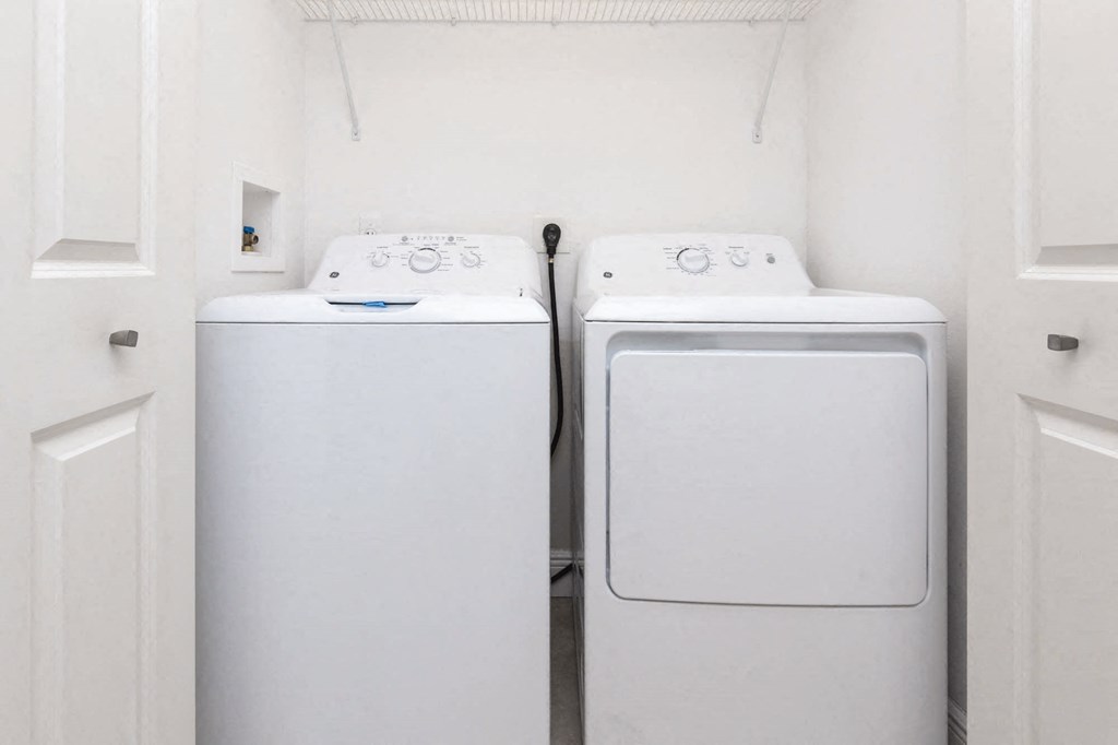 Two white front loading washing machines in a small laundry room.