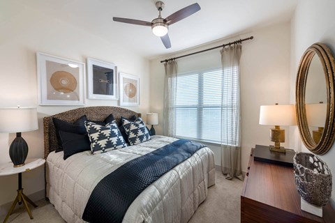 A bedroom with a large bed and a ceiling fan.
