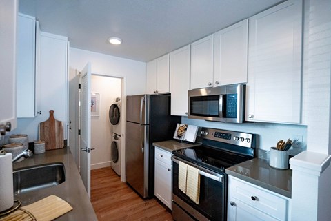 A kitchen with white cabinets and black appliances.