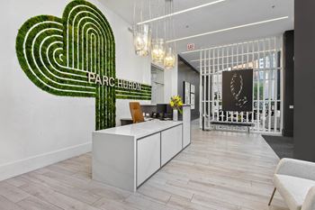a lobby with a large green logo on the wall and a reception desk in front of it