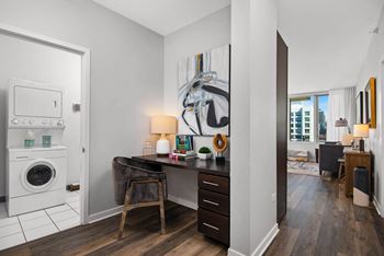 a desk with a chair and lamp and a washer and dryer in a room with