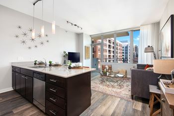 a kitchen with a large center island next to a living room with a couch and a tv