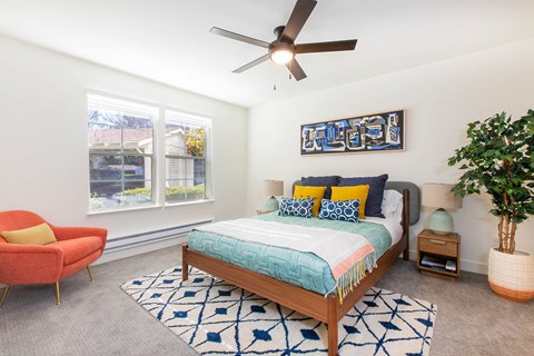 A bedroom with a bed, a chair, and a ceiling fan.