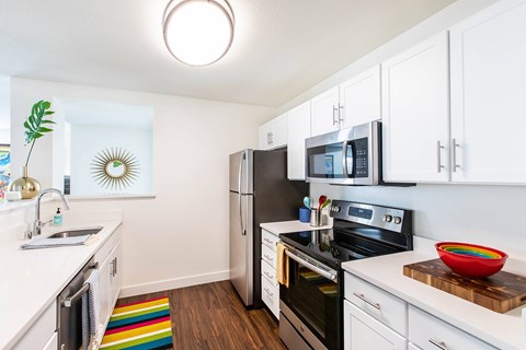 A kitchen with white cabinets and a black refrigerator.