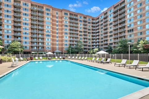 A large swimming pool in front of a multi-story apartment building.