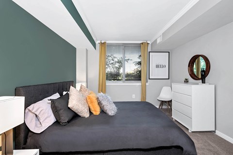 A bedroom with a grey bed and a white dresser.