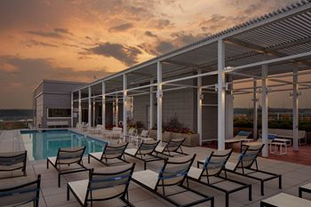 A poolside area with chairs and a building in the background.
