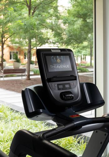 A black exercise bike with the brand name THEAVENUE on the display screen.