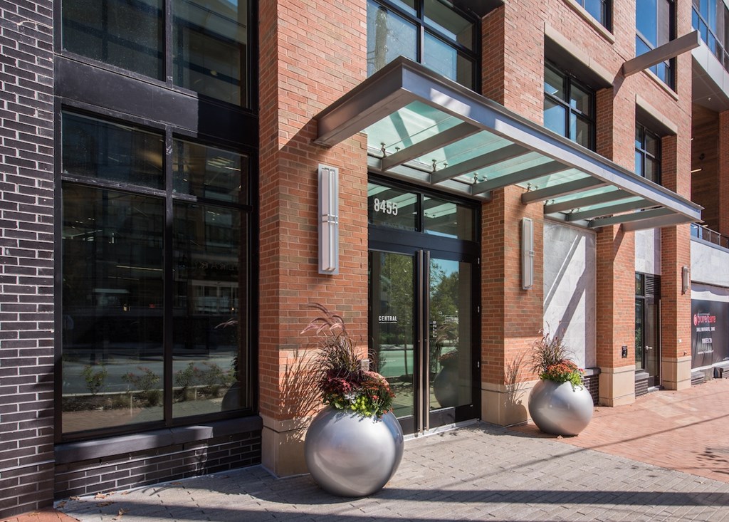 A modern building with a glass entrance and two large planters in front.