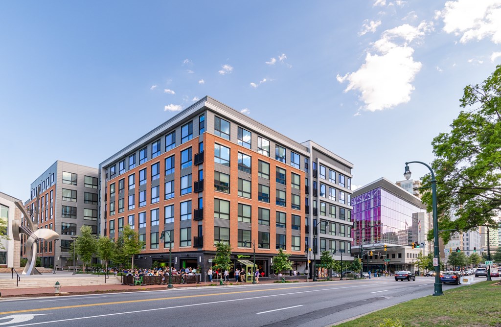 A modern building with a glass facade is situated on a street corner.