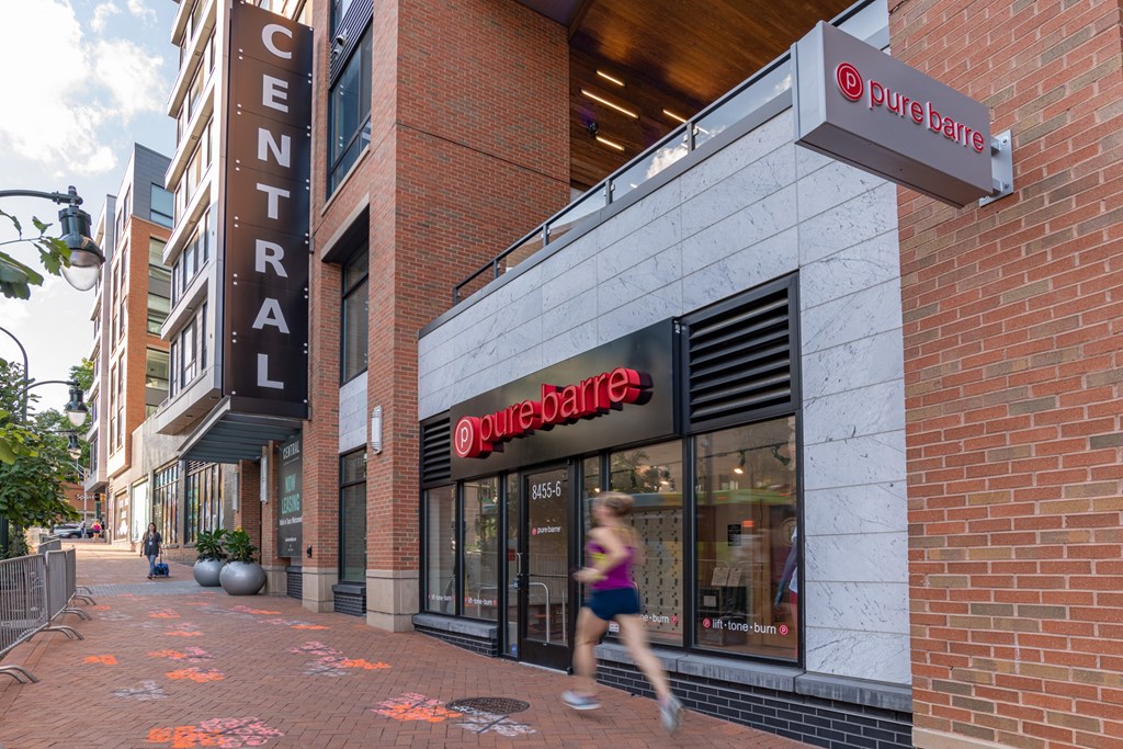 A woman runs past a Pure Barre studio on a city sidewalk.