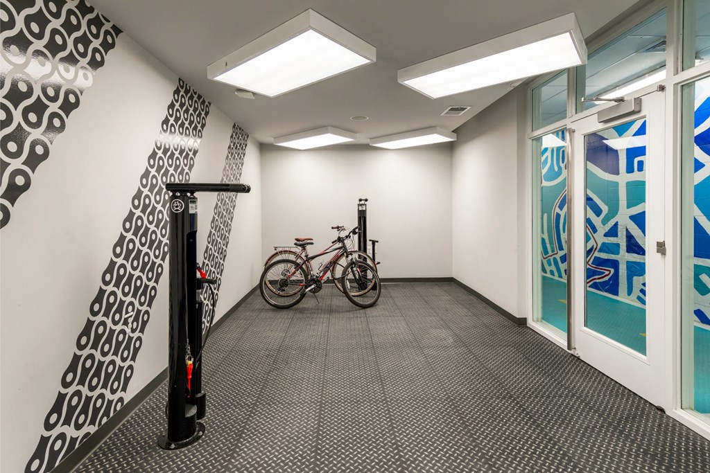 A bicycle is parked in a hallway with a black and white patterned wall and a glass door.