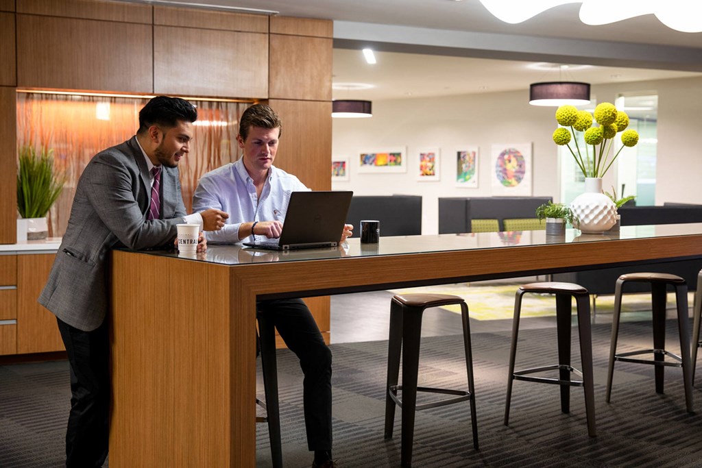 Two men are working on laptops in a modern office setting.