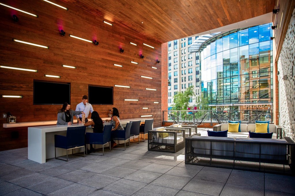 A group of people are sitting at a bar in a room with wooden walls.