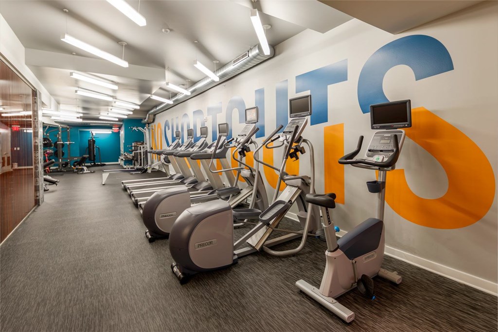 A gym with a row of exercise bikes and a wall with the word