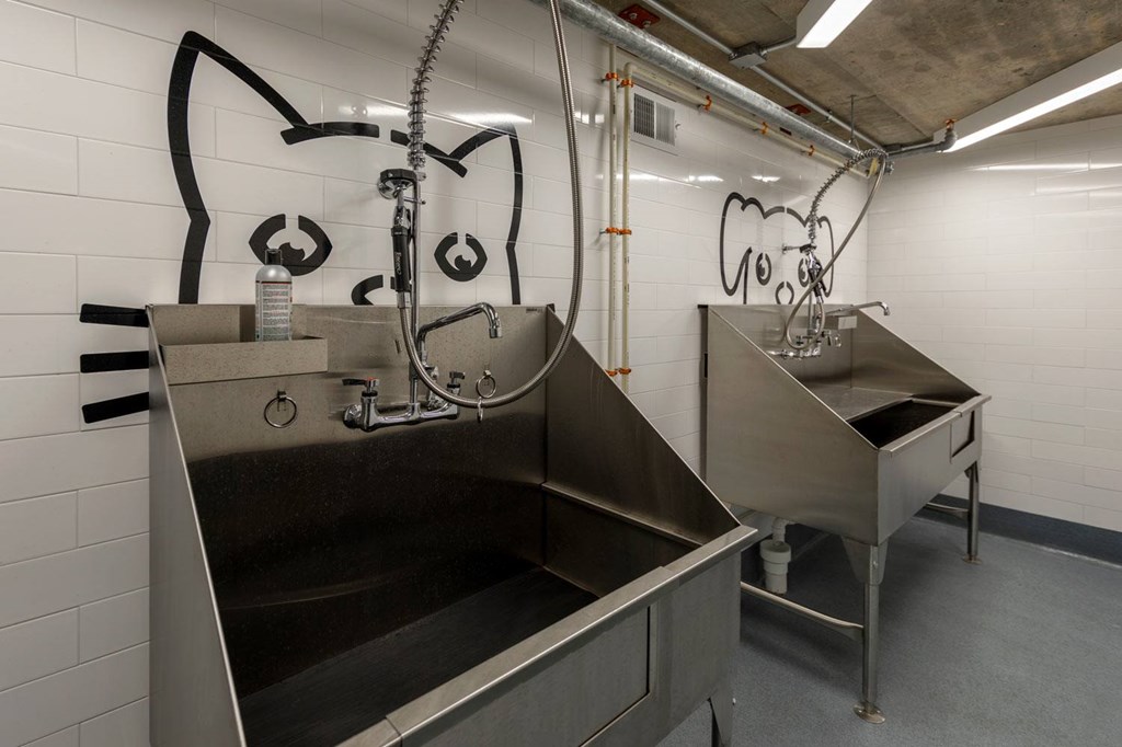 A cat-shaped water fountain is located in a room with a grey floor and white walls.