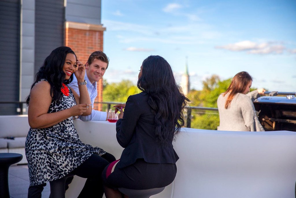 Three people are sitting on a white couch outside.