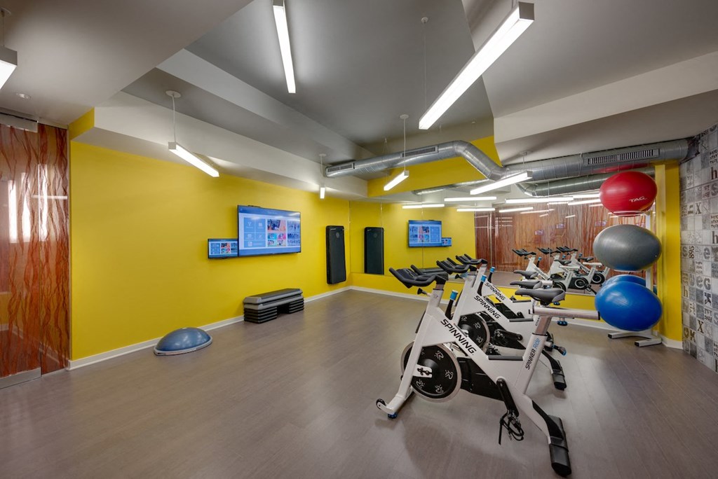 A gym with a yellow wall and exercise equipment.