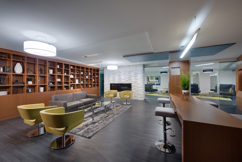 A modern office space with a long wooden bookshelf and yellow chairs.