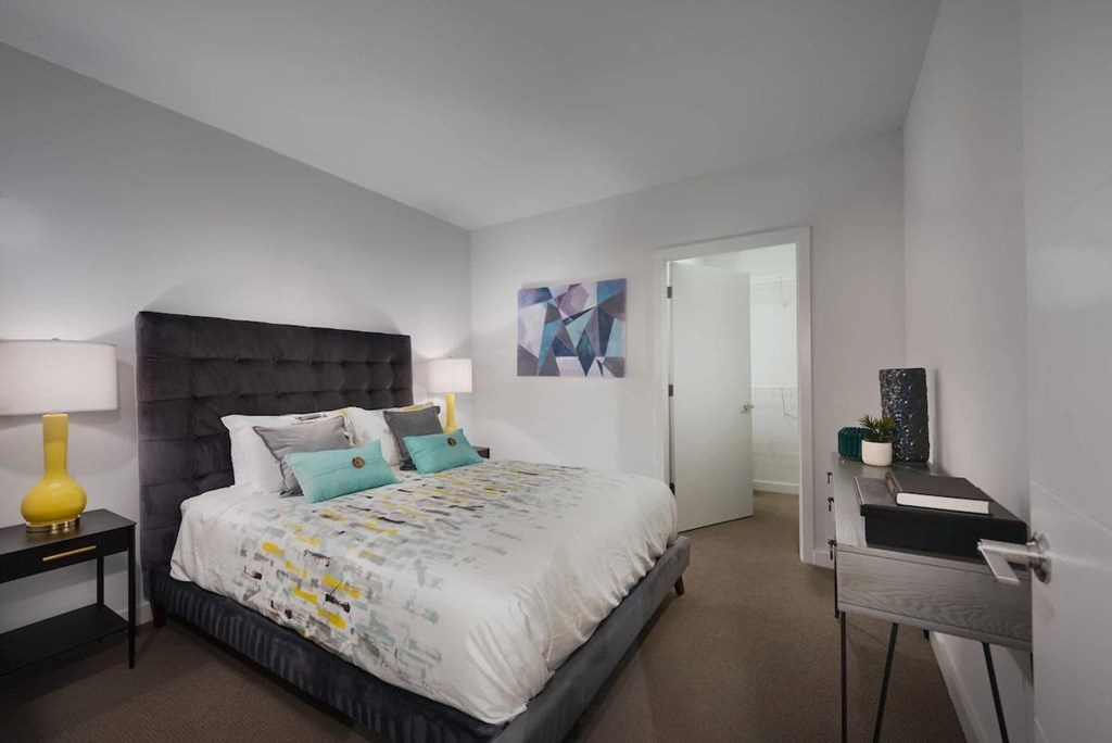 A bedroom with a large bed and a nightstand with a lamp.