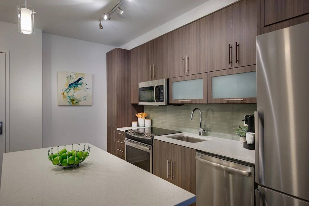 A modern kitchen with a stainless steel refrigerator, microwave, and oven.