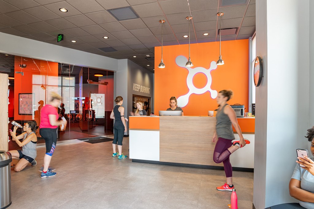 A gym with orange walls and people exercising.