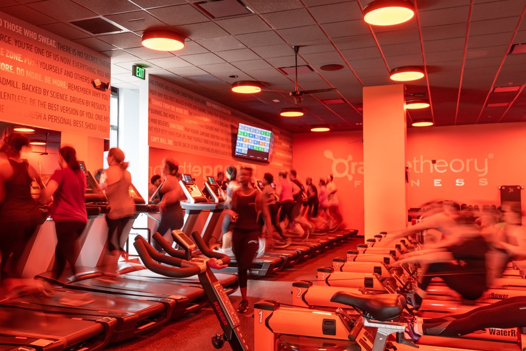 A gym with people exercising and treadmills.