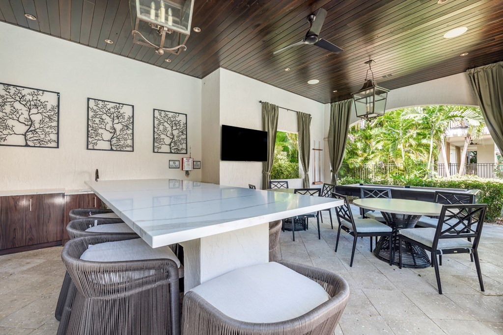 A patio with a table, chairs and a television.