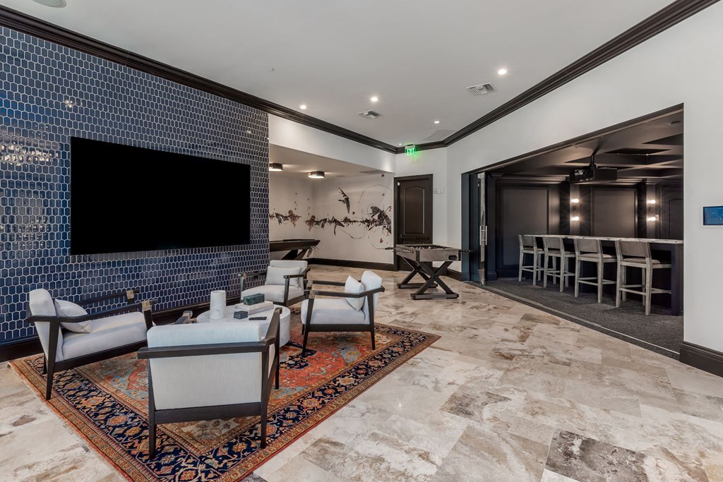 A living room with a blue tiled wall and a flat screen TV.