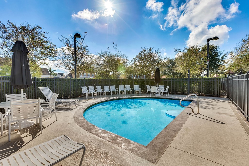 A sunny day at the pool with chairs and umbrellas.