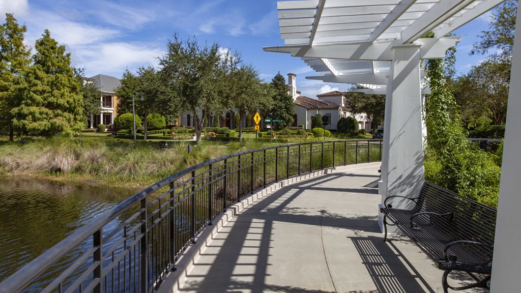 A walkway with a metal railing runs alongside a body of water.