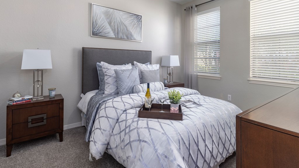 A bedroom with a bed, nightstand, and window.
