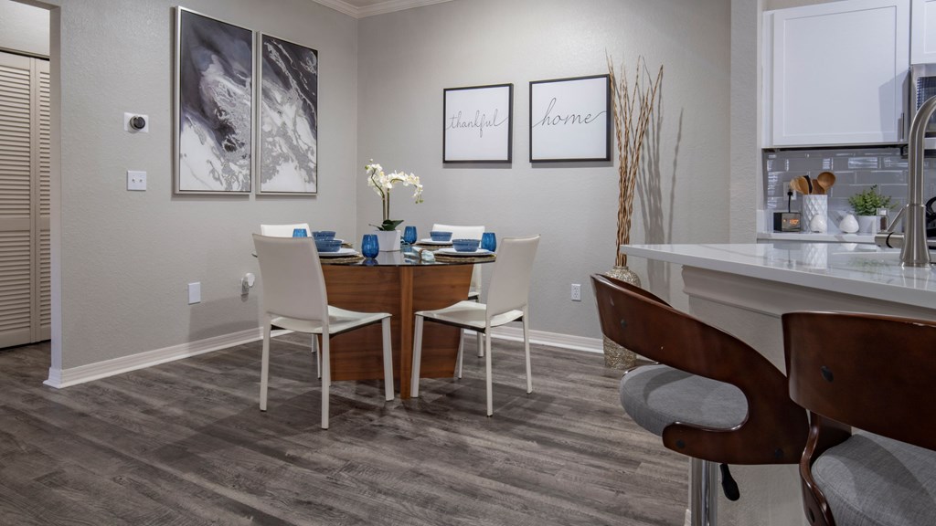 A dining room with a wooden table and white chairs.
