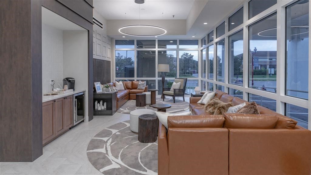 A modern living room with a brown leather sofa and a kitchen area with a sink and stove.
