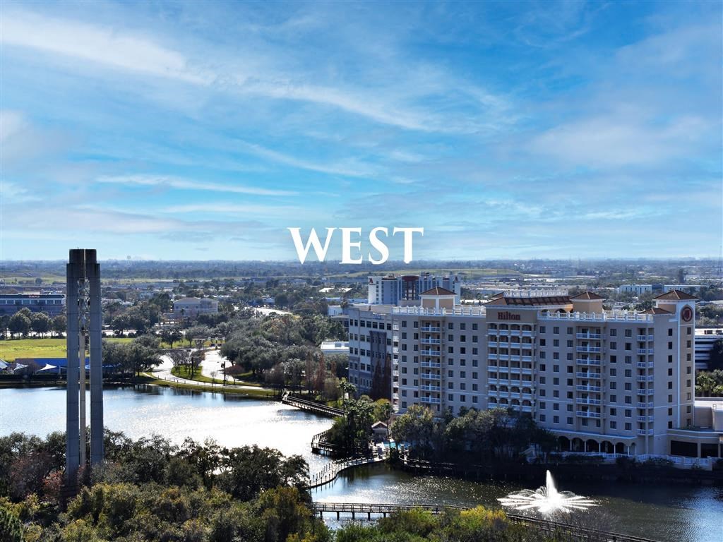 A view of a city with a large white building and a fountain in the foreground.