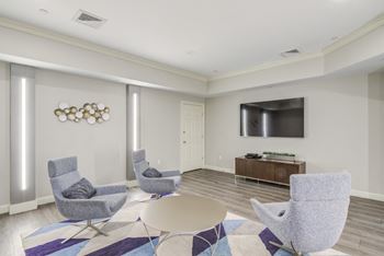 a living room with chairs and a table and a television