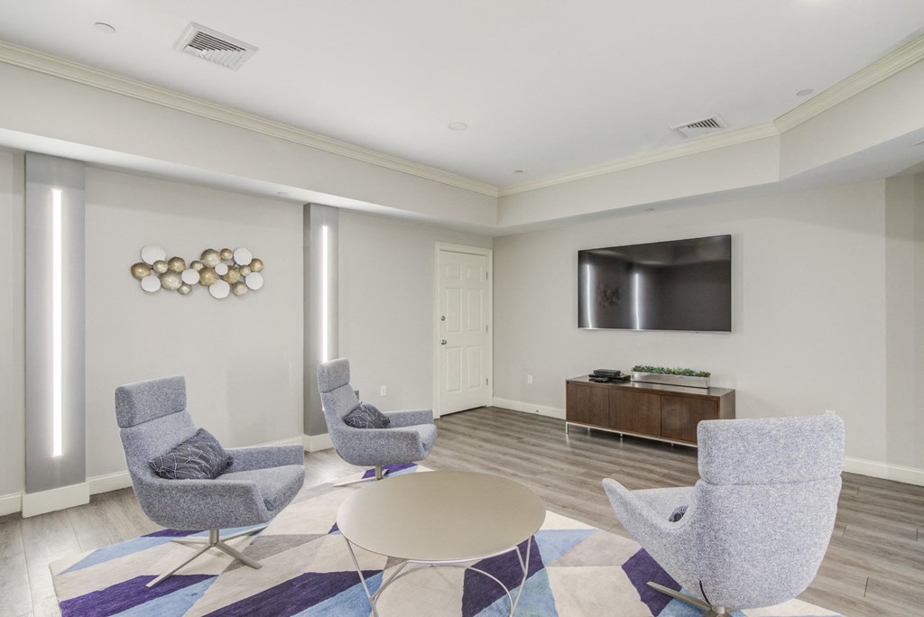 a living room with chairs and a table and a television