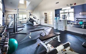a gym with cardio equipment and weights on the floor