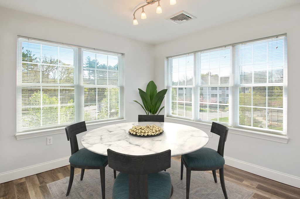 a dining room with large windows and a marble table and chairs
