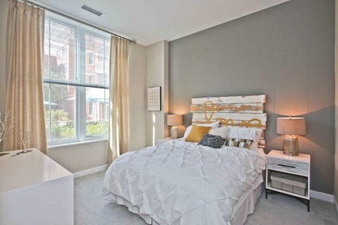 A bedroom with a large bed and a window with curtains.