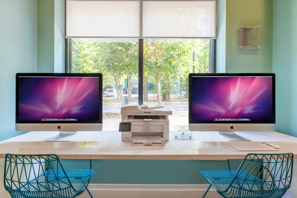 Two computer monitors on a desk with a window in the background.