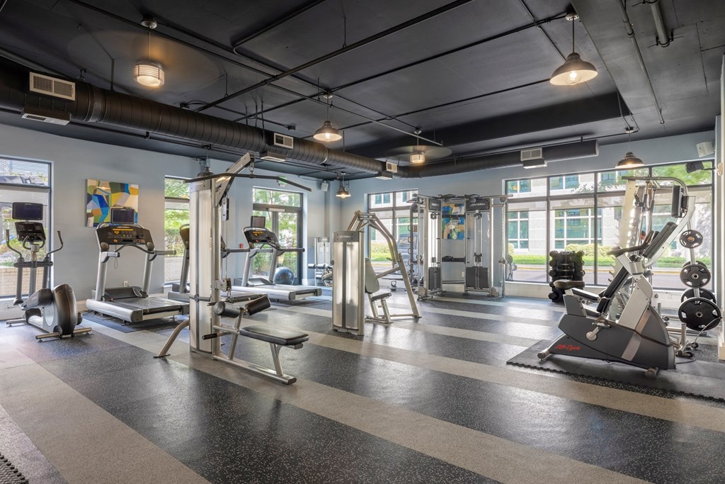 A gym with a variety of equipment including treadmills, weights, and exercise machines.