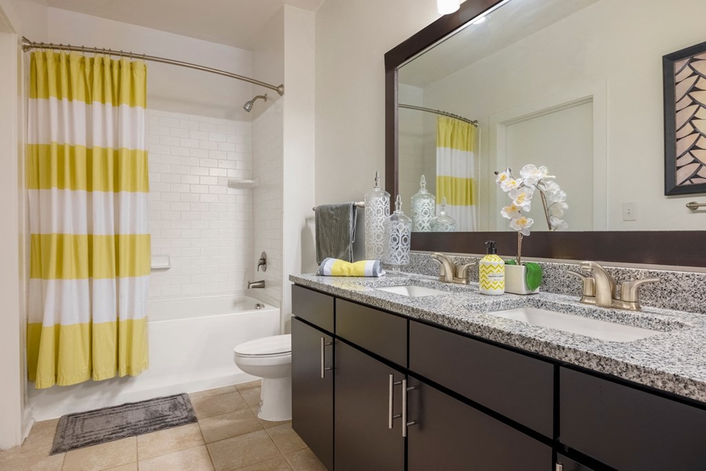 A bathroom with a yellow and white striped shower curtain.