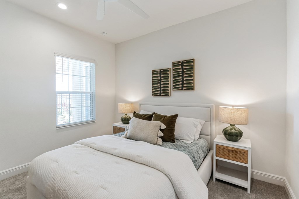 a bedroom with a bed and two nightstands and a window