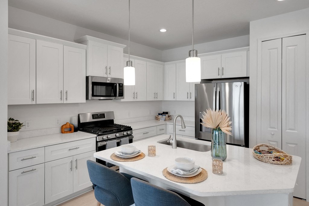 a kitchen with white cabinets and a marble counter top