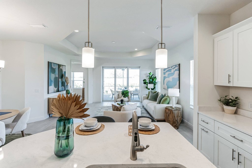 an open kitchen and living room with white cabinets and a white counter top